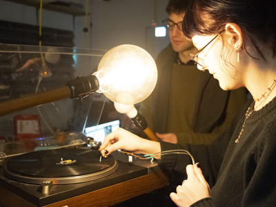 Students working with a record on a turntable and lightbulbs.